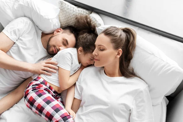 Šťastná rodina v pyžamu spí v posteli doma — Stock fotografie