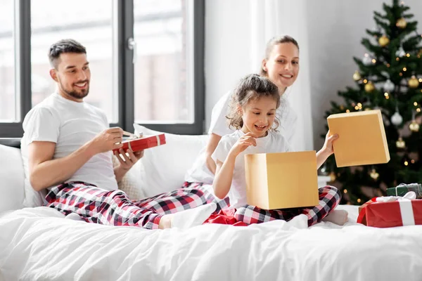 Happy family with christmas gifts in bed at home — Stock Photo, Image