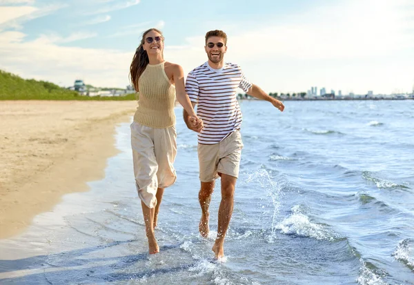 Felice coppia che corre lungo la spiaggia estiva — Foto Stock