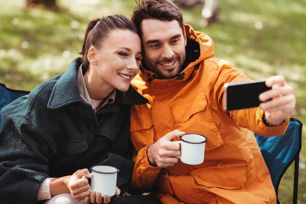 Coppia bere il tè e prendere selfie al campo tenda — Foto Stock