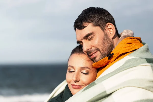 Счастливая пара в теплом одеяле на осеннем пляже — стоковое фото