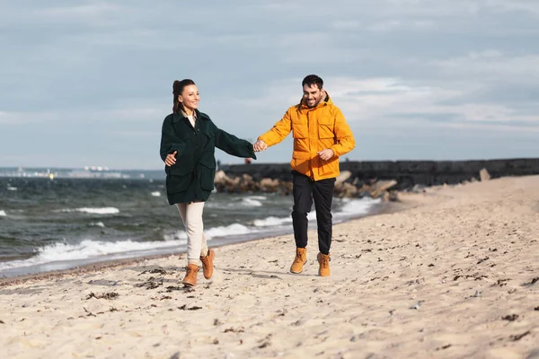 Пара бежит вдоль осеннего пляжа — стоковое фото