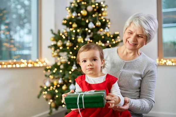 Grand-mère et bébé fille avec cadeau de Noël Image En Vente