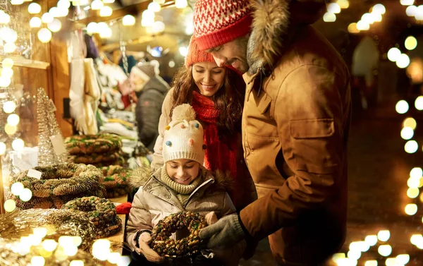 Glückliche Familie kauft Kranz auf Weihnachtsmarkt — Stockfoto