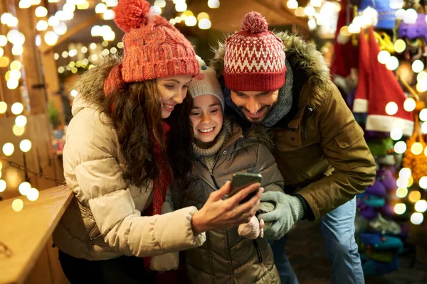 Famille heureuse avec smartphone au marché de Noël — Photo