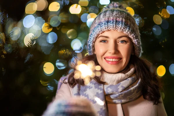 Happy woman with sparkler over christmas lights — Stock Photo, Image