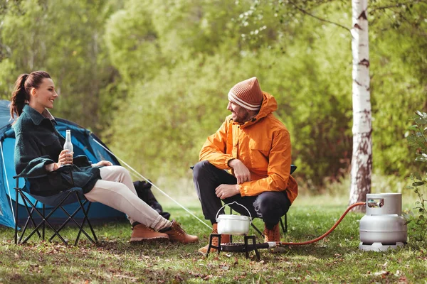 Çadır kampında bira içip yemek pişiren çift. — Stok fotoğraf