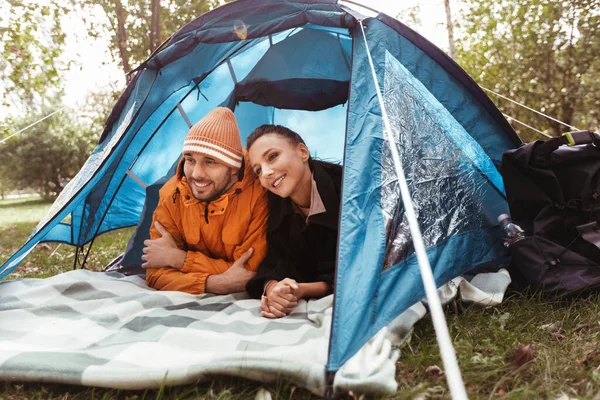 Happy couple lying inside tent at campsite — Stock Photo, Image