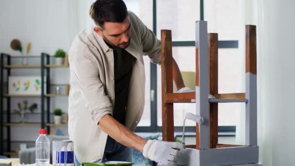 Чоловік малює старий стіл в сірому кольорі вдома — стокове відео