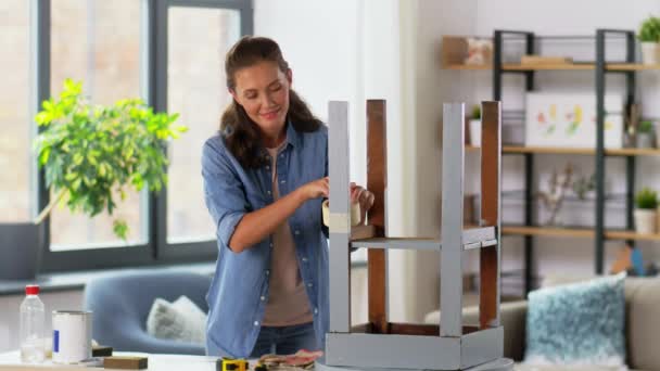 Vrouw plakken masking tape naar tafel voor repaint — Stockvideo