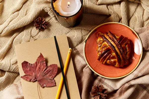 Pamiętnik, ołówek, bułka cynamonowa i świeca jesienią — Zdjęcie stockowe