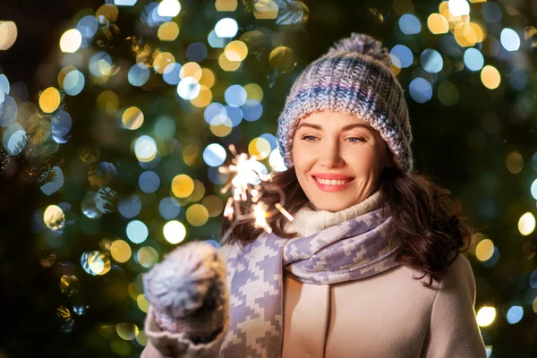 Happy woman with sparkler over christmas lights — Stock Photo, Image