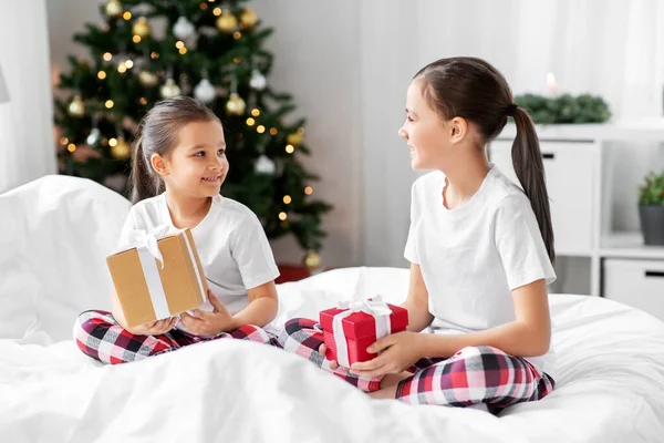 Niñas felices con regalos de Navidad en la cama en casa — Foto de Stock