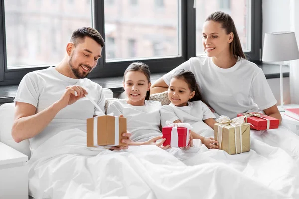 Happy family with christmas gifts in bed at home — Stock Photo, Image
