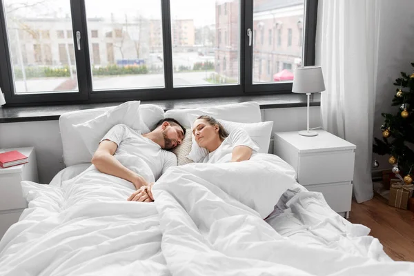 Пара спить в ліжку вдома на Різдво — стокове фото