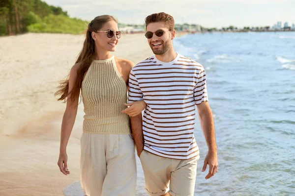 Casal feliz andando na água ao longo da praia de verão — Fotografia de Stock