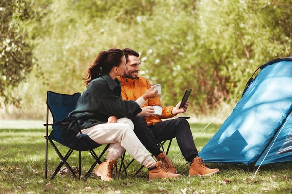 Casal com tablet pc beber chá no acampamento tenda — Fotografia de Stock