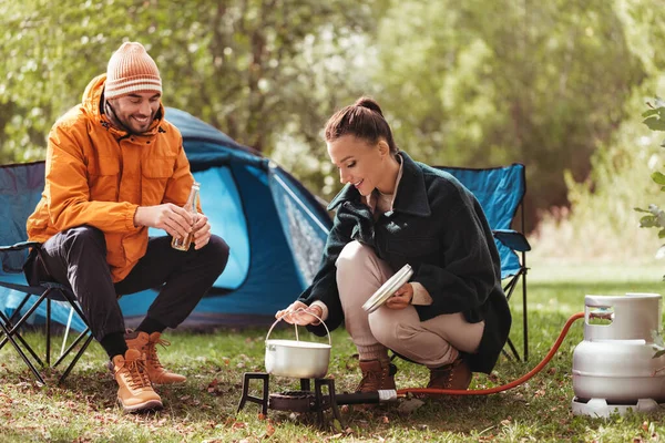 Par dricka öl och laga mat på tältlägret Stockfoto