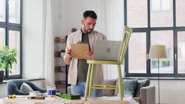 Hombre con portátil preparando silla vieja para la renovación — Vídeos de Stock