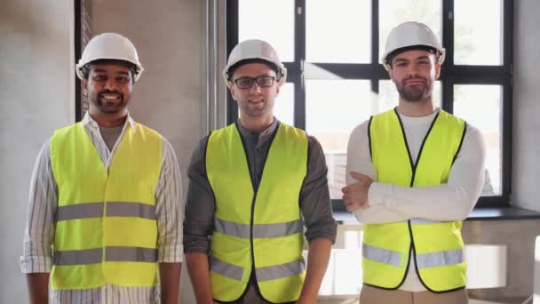 Счастливые улыбающиеся мужчины-архитекторы в шлемах в офисе — стоковое видео