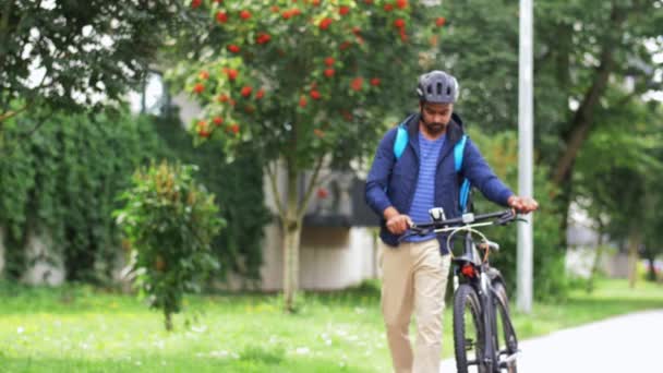 Homem de entrega com saco e bicicleta andando na cidade — Vídeo de Stock