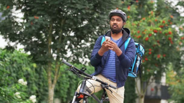 Homem de entrega com saco e bicicleta chamando no telefone — Vídeo de Stock