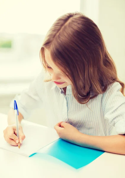 Student meisje schrijven in notitieblok op school — Stockfoto