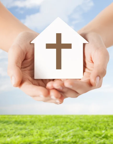 Close up of hands and paper house with cross — Stock Photo, Image