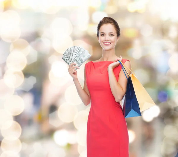 Lachende vrouw in rode jurk met shopping tassen — Stockfoto