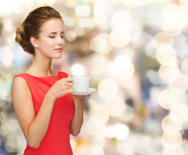 Femme souriante en robe rouge avec tasse de café — Photo