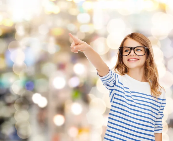 Schattig klein meisje in brillen wijzen in de lucht — Stockfoto