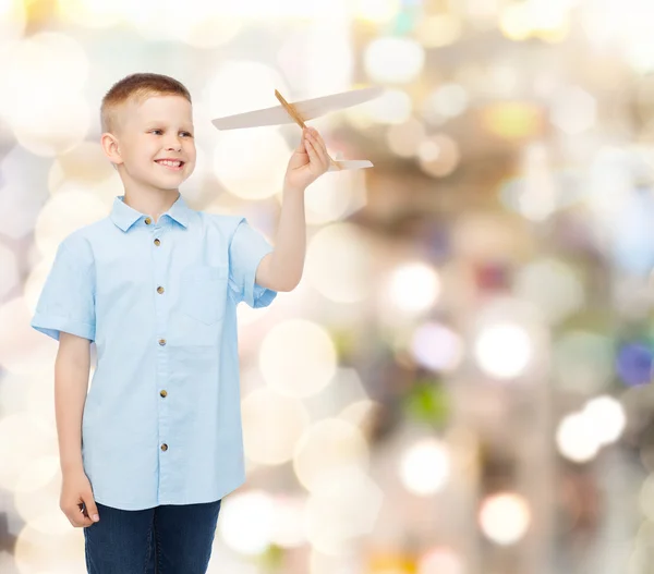 Menino sorrindo segurando um modelo de avião de madeira — Fotografia de Stock