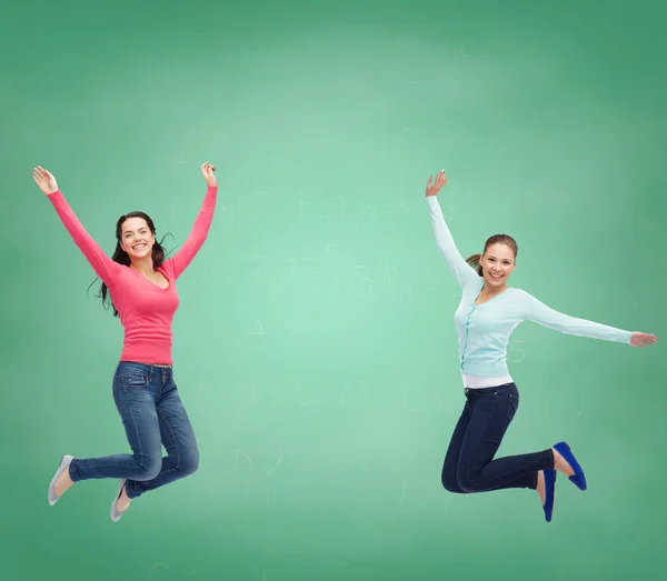 Sonrientes mujeres jóvenes saltando en el aire — Foto de Stock