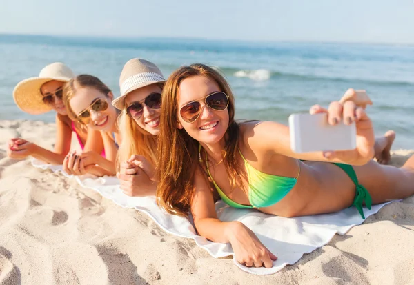 Grupo de mujeres sonrientes con teléfono inteligente en la playa — Foto de Stock