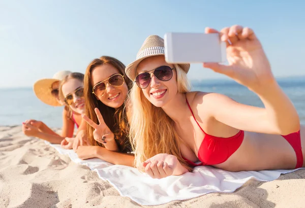 Grupo de mujeres sonrientes con teléfono inteligente en la playa —  Fotos de Stock