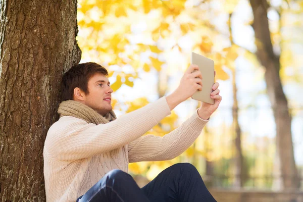 Tablet pc sonbahar Park ile genç adam gülümsüyor — Stok fotoğraf