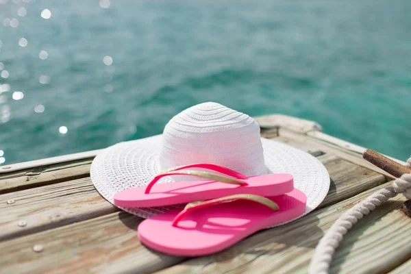 Close up van hoed en slippers aan zee — Stockfoto