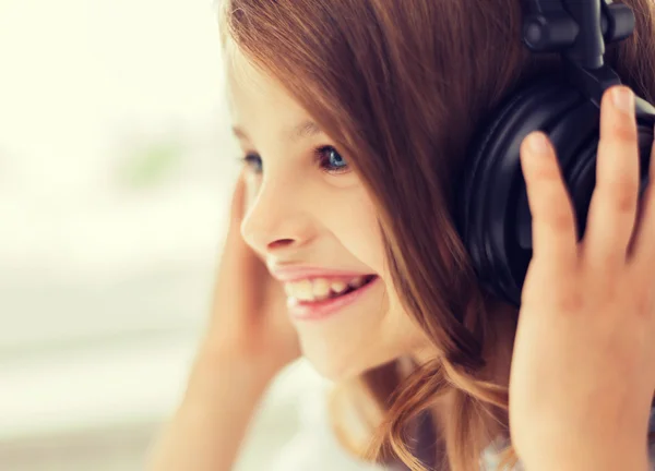 Sorrindo menina com fones de ouvido em casa — Fotografia de Stock