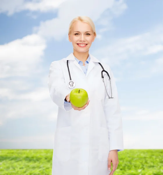 Lachende vrouwelijke arts met groene apple — Stockfoto