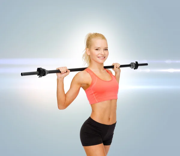 Sorrindo mulher desportiva exercitando com barbell — Fotografia de Stock