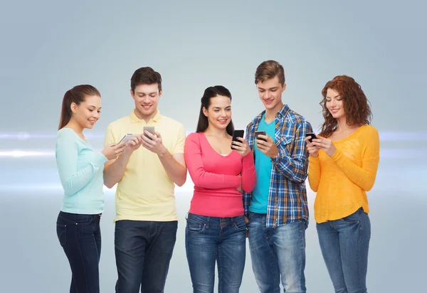 Grupa nastolatków uśmiechający się ze smartfonów — Zdjęcie stockowe
