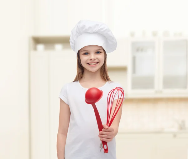 Menina sorridente em chapéu de cozinheiro com concha e batedor — Fotografia de Stock