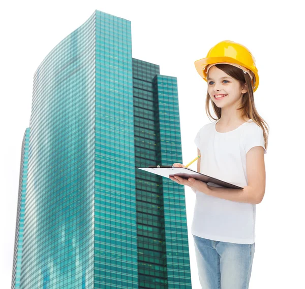 Petite fille souriante en hardhat avec presse-papiers — Photo