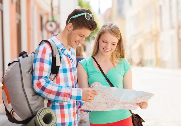 Smiling couple with map and backpack in city — Stock Photo, Image