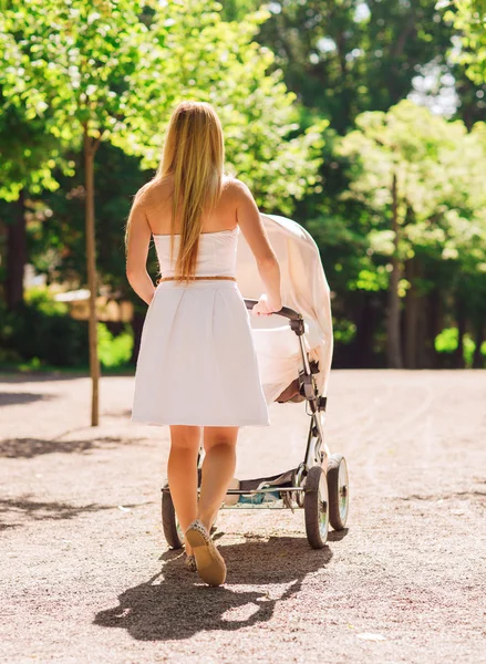 Glad mamma med barnvagn i park — Stockfoto