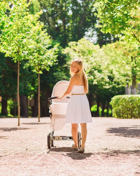 Glad mamma med barnvagn i park — Stockfoto