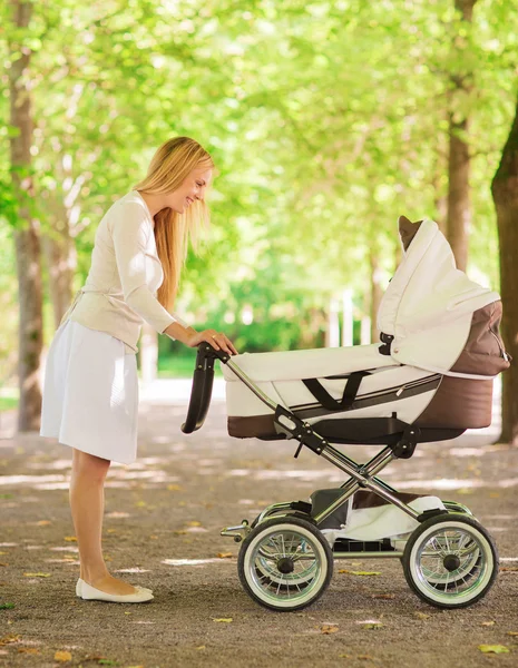 Счастливая мать с коляской в парке — стоковое фото