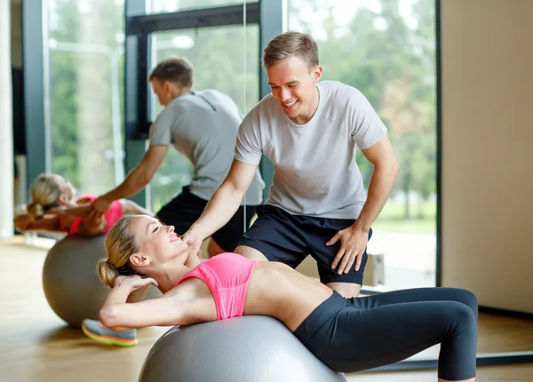 Spor salonunda kişisel antrenörüyle gülümseyen genç bir kadın. — Stok fotoğraf