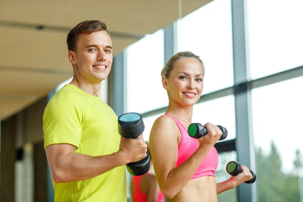 Glimlachende man en vrouw met halters in gym — Stockfoto