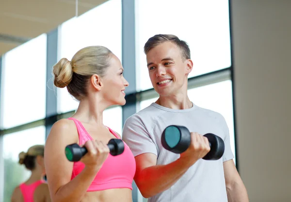 Smiling young woman with personal trainer in gym Stock Photo